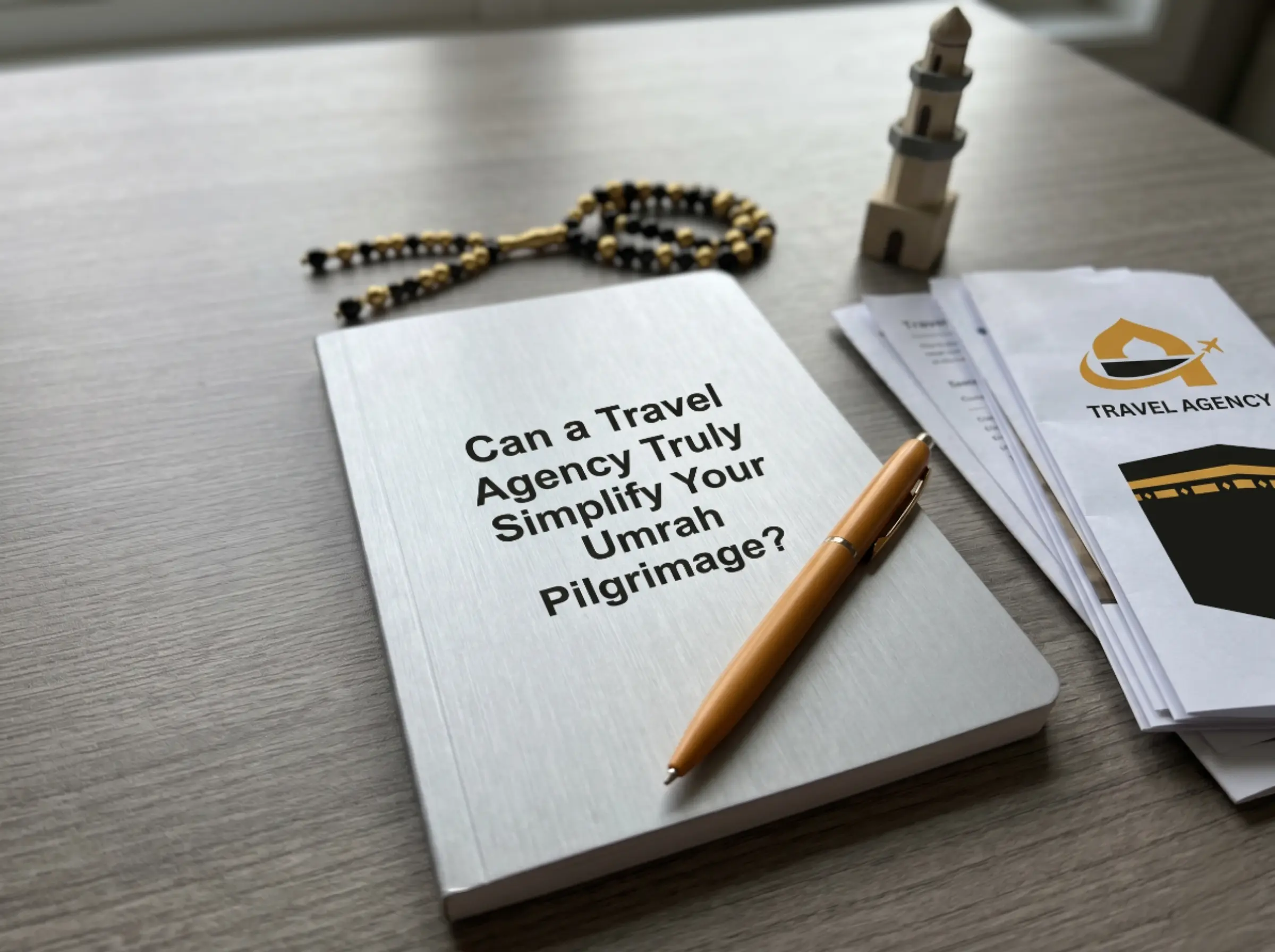 Notebook with title 'Can a Travel Agency Truly Simplify Your Umrah Pilgrimage?' surrounded by prayer beads, minaret model, and travel agency documents.